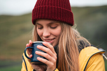 Girl looking at her mug with hot beverage while drinking at the nature