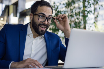 Young emotional middle eastern businessman using laptop computer, reading good news. Successful...