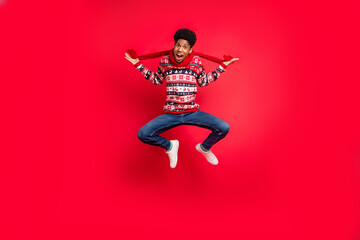 Fototapeta na wymiar Full body photo of young afro guy happy positive smile jump up scarf winter holiday isolated over red color background
