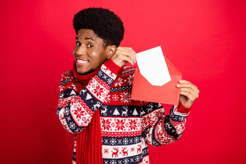 Photo of young funny brunet guy send letter wear holiday scarf sweater isolated on red color...