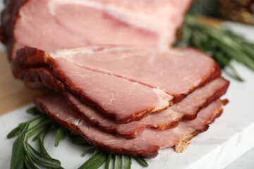 Cut delicious ham with rosemary on white table, closeup
