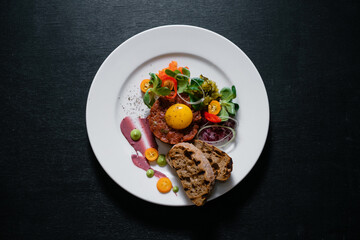 Beef tartare garnished with sauces with herbs and served with croutons.