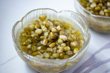 Green beans boiled sugar in a glass cup on a gray background