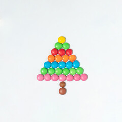 Sweet Christmas tree idea. Colorful candies on white background. Minimalistic New Year concept. Flat lay.
