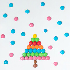 Sweet Christmas tree  and snow idea. Colorful candies on white background. Minimalistic New Year concept. Winter flat lay.