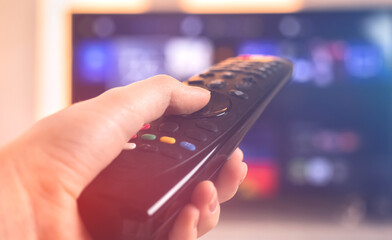 Concept person with remote control watching tv in living room, selective focus