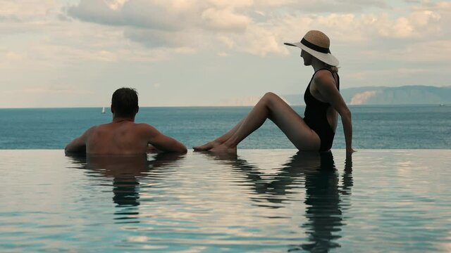 couple enjoying romantic sea view in infinity swimming pool at luxury resort