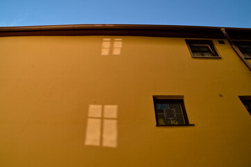Fenster, Fensterläden, Spiegelung im Glas und Lichtreflexionen an einer bunten Hauswand