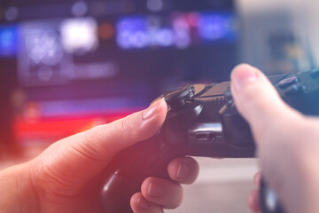 Playing video games on a console with wireless controller at home, close-up view of joystick in neon lights