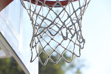 Basketball hoop with net outdoors on sunny day, closeup