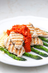 grilled poultry meat with baked red pepper sauce and green asparagus