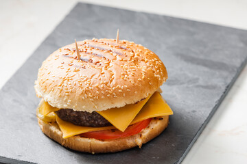 still life of cheeseburger on black plate