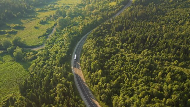 Shooting of a winding road passing through the forest from a bird's eye view. Filmed 4k, drone video.