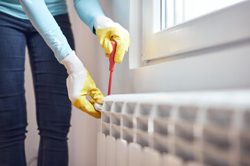Handyman with gloves fixing and bleeding air from central heating gas radiator system at home.