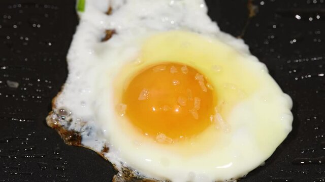 Sprinkling green scallion on sunny side up eggs