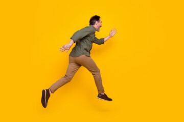 Fototapeta na wymiar Full length body size profile side view of attractive cheerful man running fast isolated over bright yellow color background