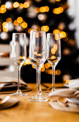 Empty champagne glasses stand on the festive table against the background of the Christmas tree