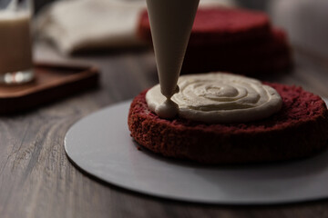 Chef or baker decorating cake with white whipped cream.Soft fokus