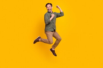 Fototapeta na wymiar Full length body size view of attractive cheerful lucky man jumping rejoicing isolated over vivid yellow color background