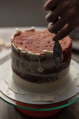 Chef or baker decorating cake with white whipped cream.Soft fokus
