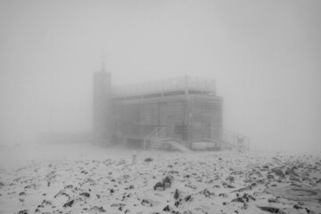 Lonely snow-covered building in the fog. Black and white.