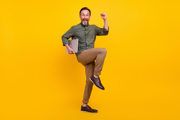 Fototapeta na wymiar Full size photo of mature man happy positive smile rejoice victory hold laptop isolated over yellow color background