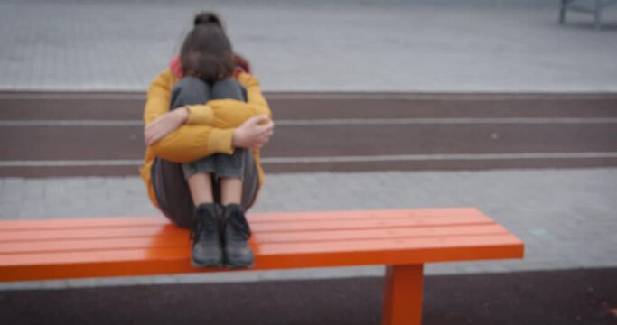 Depressed teen on playground. A teen in depression sits on the bench on the playground.