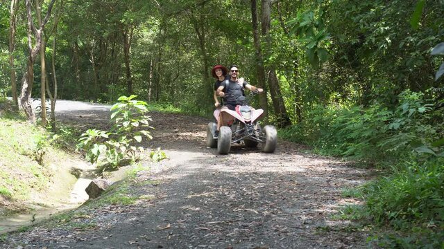 happy young Couple driving quad bike or ATV in adventure trip in nature park . off road in countryside