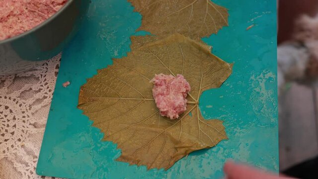 People cook dolma food.
Grape leaves stuffed with minced meat.