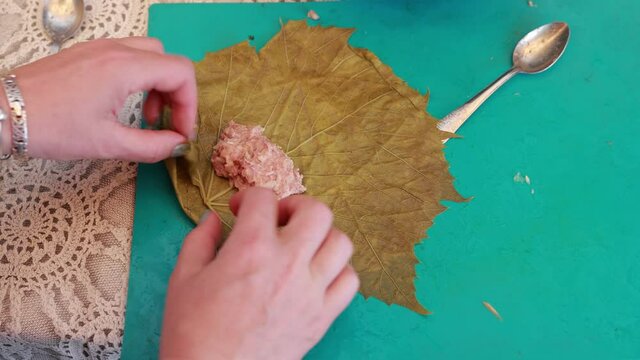 People cook dolma food.
Grape leaves stuffed with minced meat.