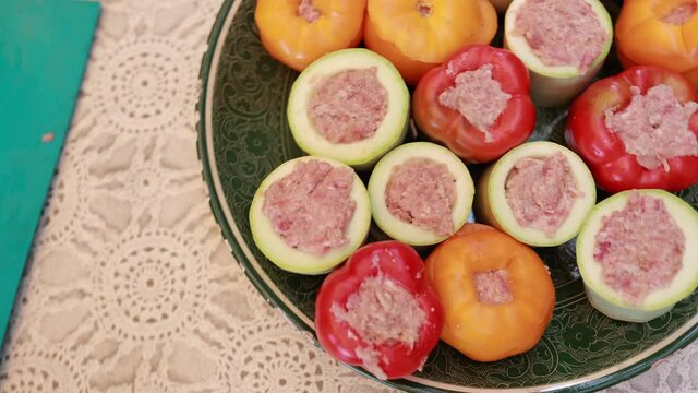 People hands are preparing food. Peppers, tomatoes, zucchini and grape leaves stuffed with minced meat.