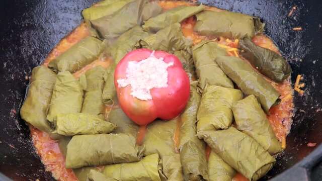 People cook dolma food.
Grape leaves stuffed with minced meat.