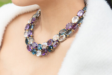 A necklace made of silver and amethyst and aquamarine and white gemstones is worn on the neck of an...