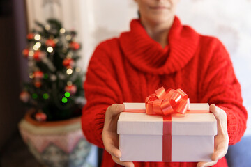 Obraz na płótnie Canvas Woman in a red jersey giving a Christmas present