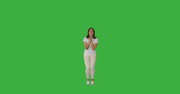 Amazed woman jumping in excitement and celebrating victory with arms raised over green background