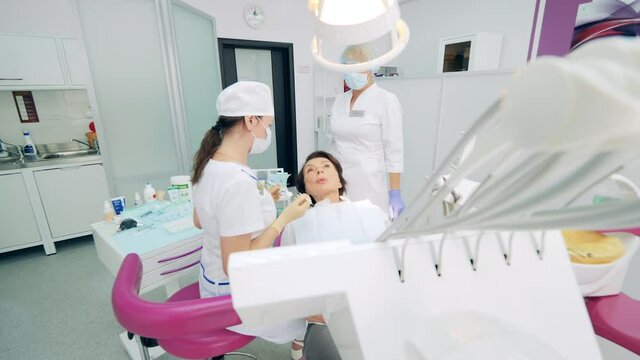 Female patient is talking to dentists while being in a chair