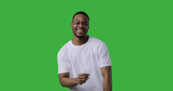 Happy african american man singing song and dancing over green background