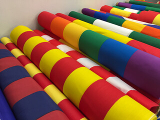 Rolls of fabrics for the flags of the regions of Spain and football clubs are on the table in the fabric store for sale. Flags of Spain. A full-frame shot of colorful fabrics in a store.