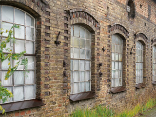Historische Ziegelwand mit Fenstern aus der Jahrhundertwende eines Industriegebäudes