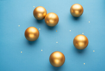 Gold Christmas balls on a light blue background with stars