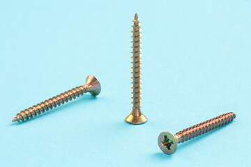 Three screws on a blue background, one standing and two diagonally