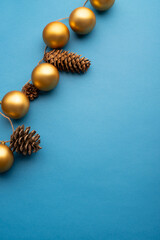 Gold Christmas balls and cones on a light blue background. Top view. 