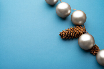 Silver Christmas balls and cones on a light blue background.