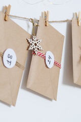 Hand made advent calendar. Preparation to christmas concept. Craft envelopes arranged on a white wall. Selective focus.