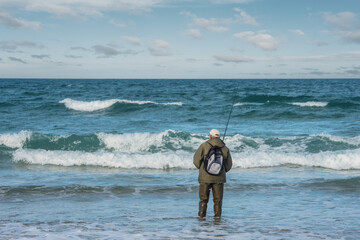 senior fishing with surfcasting technique on the beach