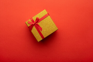 Red and gold gift box on a bright red background. Flat lay, top view.
