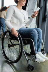 cropped view of happy businesswoman with physical disability using mobile phone in office