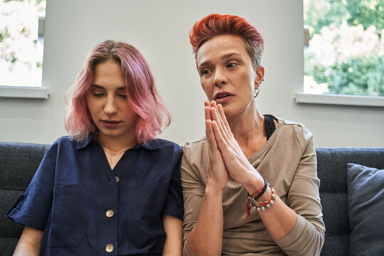 Two lesbian married women sitting at the sofa and discussing their problems