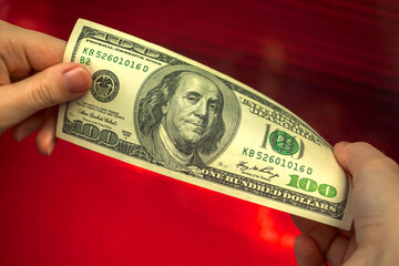 Dollar go down, US money on a red stock chart currency exchange rate background hands close-up photo