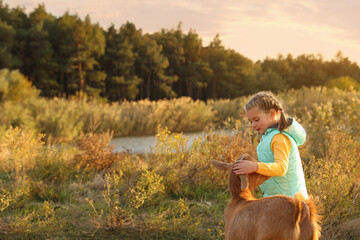 Farm animal. Cute little girl with goat on pasture, space for text